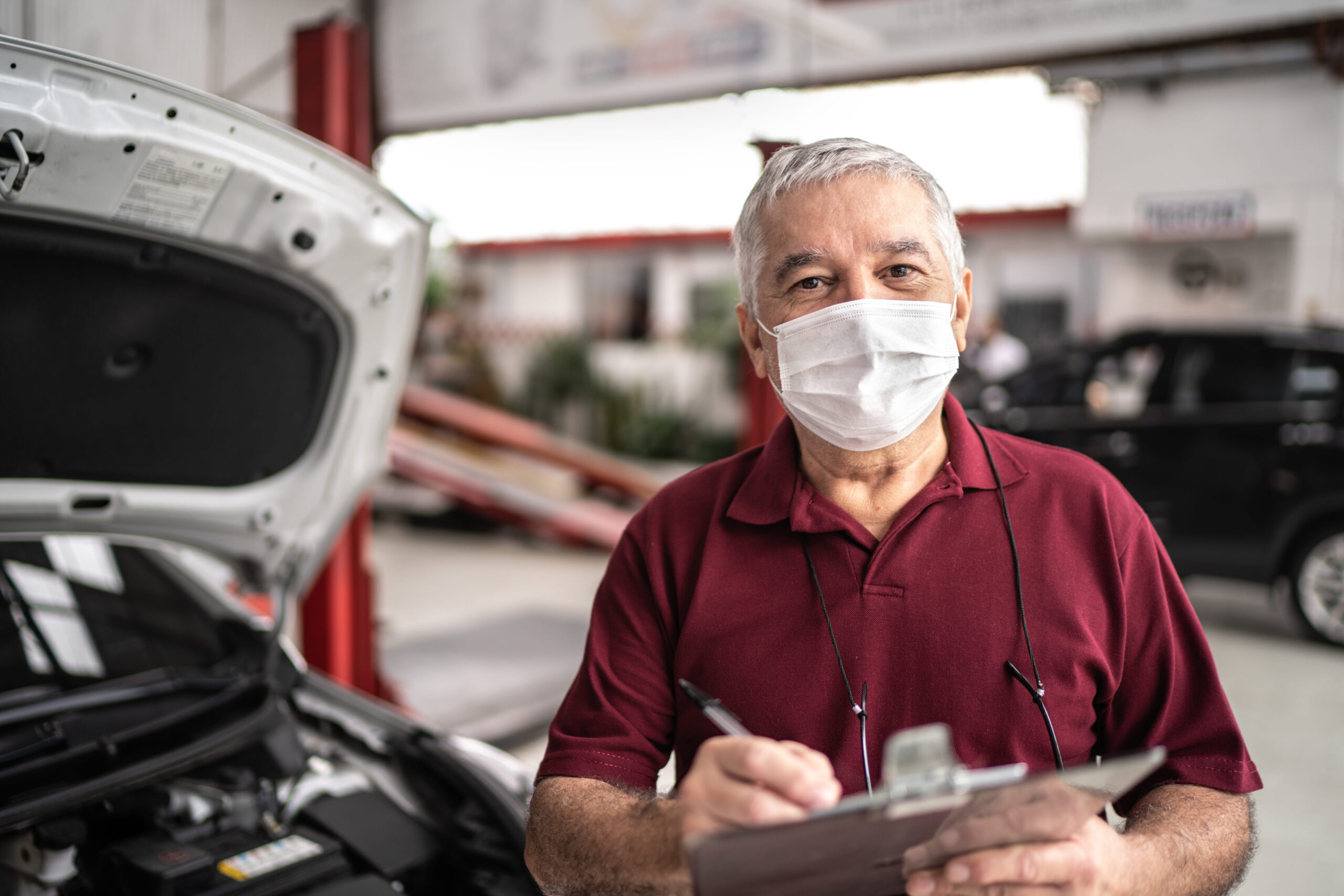 Portrait of auto mechanic senior man with face mask at auto repair shop
